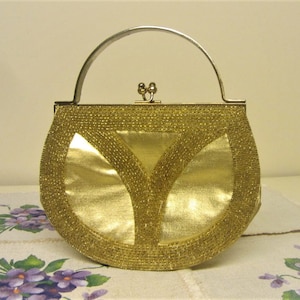 May include: A gold beaded evening bag with a silver handle and clasp. The bag is shaped like a half-circle and has a smooth, shiny finish.