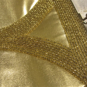 May include: A gold-colored purse with a beaded design. The purse has a clasp closure and a small handle.