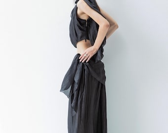 May include: A black two-piece outfit with a flowing design. The top is a sleeveless crop top with a back zip. The bottom is a long, pleated skirt. The outfit is made of a lightweight, possibly silk-like fabric.