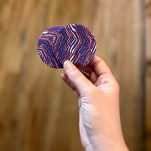 May include: Two round coasters with a blue, red, and white striped pattern. The coasters are made of a textured material.