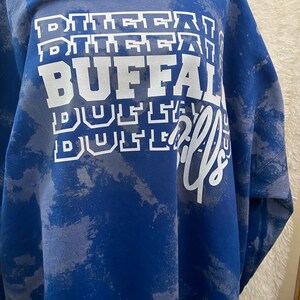 May include: A blue tie-dye sweatshirt with the words "BUFFALO" and "BUSTLE" printed in white.