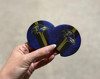 Peut inclure: Deux dessous de verre circulaires pour voiture avec le logo des Ravens de Baltimore. Les dessous de verre sont bleu marine avec des rayures noires et dorées et le logo du corbeau de l'équipe. Ils sont conçus pour les porte-gobelets de voiture.