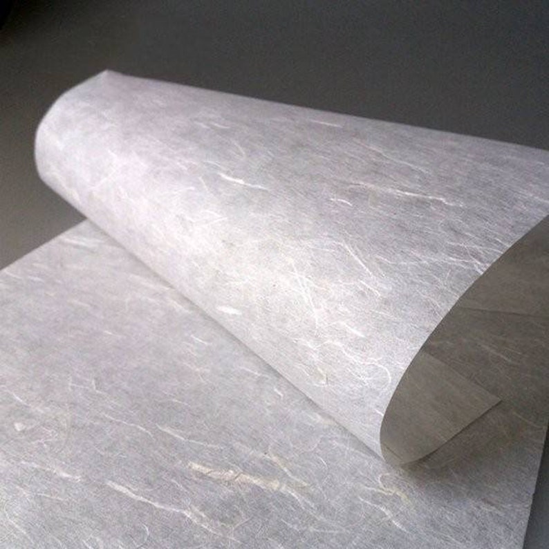 May include: A sheet of white textured paper with a subtle, uneven surface. The paper is folded in half, revealing the texture of the paper.