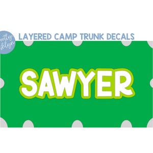 May include: A green decal with the name "SAWYER" in white and green lettering. The decal is surrounded by white polka dots and the text "LAYERED CAMP TRUNK DECALS". A logo in a blue circle reads "Sweetly Ashlyn".