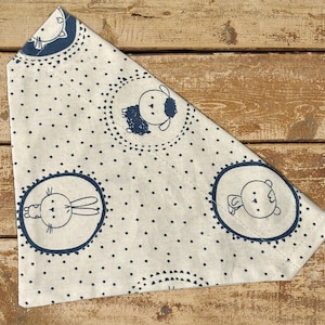 May include: A white fabric bandana with a blue polka dot pattern and black animal illustrations. The bandana features a sheep, a rabbit, and a bear.