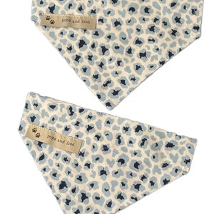May include: Two blue and white leopard print dog bandanas with the text "pops and fred" on a brown tag.