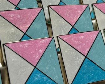 May include: A collection of square-shaped pins with a geometric design. The pins are made of metal and have a shiny, iridescent finish. The design features four triangles in alternating colors of pink, blue, and white.