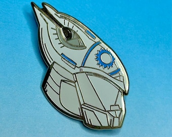 May include: A white and blue enamel pin featuring a stylized robot head with a single eye and a circular design on the forehead.
