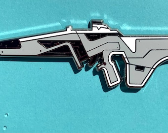 May include: A silver and white futuristic-style gun pin. The pin is detailed with black lines and has a white outline.