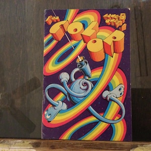 May include: A vintage book cover with the title "Coloro" in 3D orange letters, set against a rainbow and a purple background. A blue, cartoon-like character with flexible limbs is featured. The text "For Adults Only" is also visible.