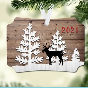 Könnte beinhalten: Ein Sublimationsdesign mit rustikalem Holzhintergrund, weißen Silhouettenbäumen, einem schwarzen Silhouettenhirsch und dem Text "2021" in Rot.