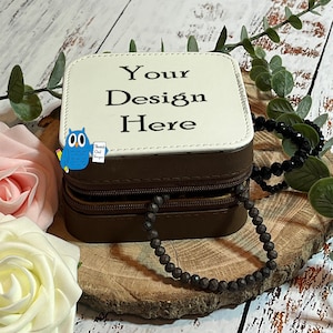 May include: A brown faux leather box with a zipper closure and a white top. The top has the text "Your Design Here" printed on it. A black beaded chain is wrapped around the box.