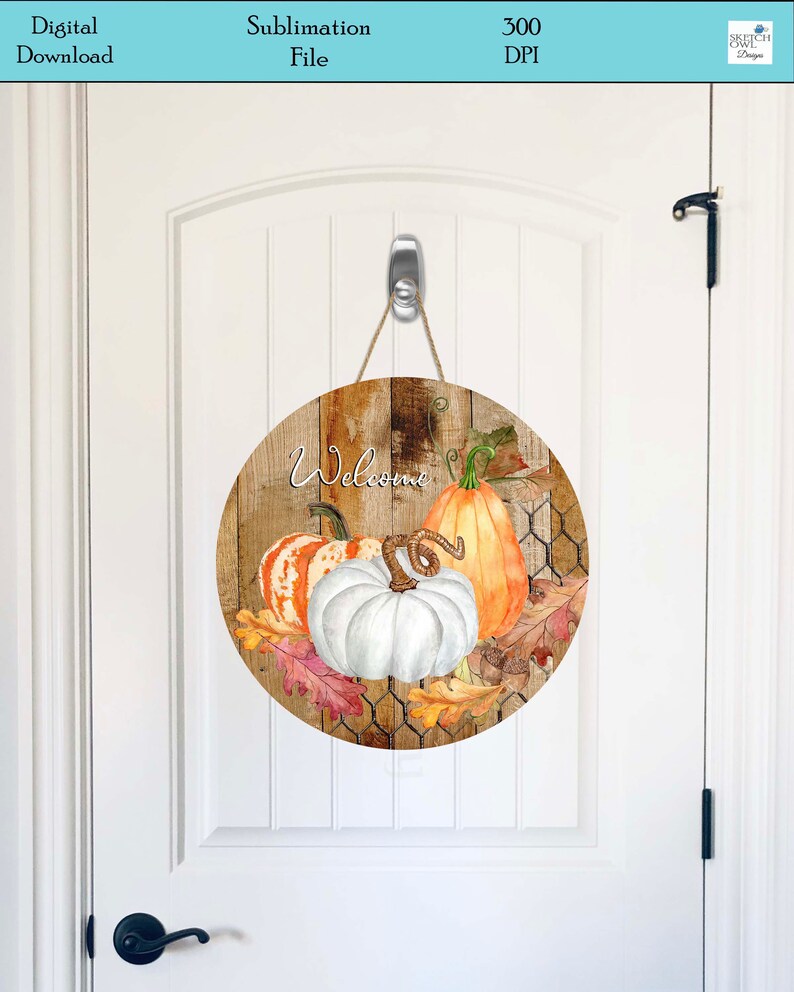 May include: A round wooden sign with a rustic woodgrain background and a white chicken wire pattern. The sign features a white pumpkin, an orange pumpkin, and a striped pumpkin with green leaves. The text "Welcome" is written in white cursive lettering.
