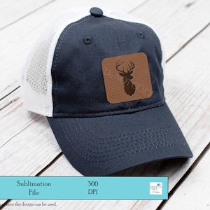 May include: A blue and white trucker hat with a brown leather patch featuring a silhouette of a deer with antlers. The hat is on a wooden surface.