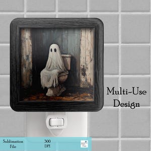 May include: A black framed nightlight with a spooky image of a ghost sitting on a toilet. The image is set in a bathroom with a wooden floor and a blue wall. The text "Multi-Use Design" is printed below the image.