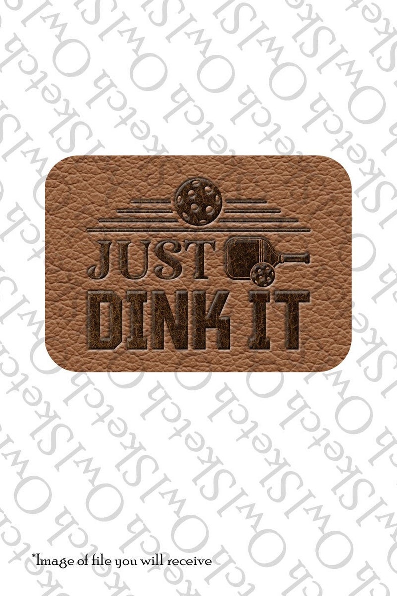 K&ouml;nnte beinhalten: Ein braunes Leder-Patch mit dem Text "JUST DINK IT" in dunkelbrauner Schrift. Der Text befindet sich &uuml;ber einer Silhouette eines Pickleball-Schl&auml;gers und -Balls.