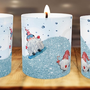 May include: Three white pillar candles with a winter gnome theme. Each candle features a different gnome design with blue and red accents. The candles are decorated with a blue glitter effect and white snowflakes.