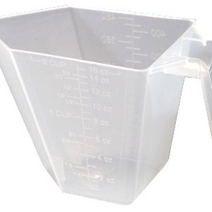 Puede incluir: Un vaso medidor de plástico transparente con asa. El vaso tiene marcas para onzas y tazas.