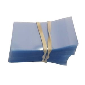May include: A stack of clear plastic sleeves bundled together with a rubber band. The sleeves are translucent and have a slight blue tint.