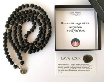 以下が含まれることがあります： 黒色の溶岩石ビーズネックレス、シルバーのアクセントと蓮の花のチャーム付き。 ネックレスは、「There are blessings hidden everywhere. I will find them.」と書かれたカードが入った箱と一緒に表示されています。