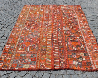 May include: A large, rectangular, orange and red rug with a geometric pattern. The rug has a fringe border and is made of wool.