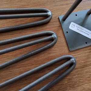 May include: Four metal hairpin legs for furniture, with a square metal plate. The plate has a sticker with the text "Sunny Coast Hairpin Legs, PH: 4383869884".