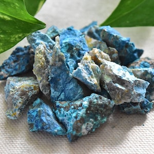 May include: A pile of rough, blue, green, and white mineral stones. The stones are irregularly shaped and have a rough, textured surface.