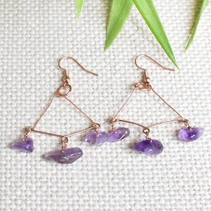 May include: A pair of dangle earrings with a geometric design. The earrings are made of rose gold wire and feature multiple amethyst stones.