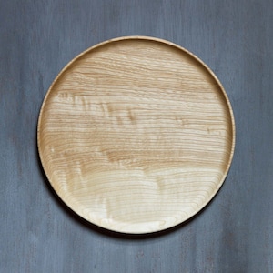 以下が含まれることがあります： 薄い茶色の木目模様の丸い木製サービングトレイ。トレイは天然木で作られており、滑らかで磨かれた仕上げになっています。