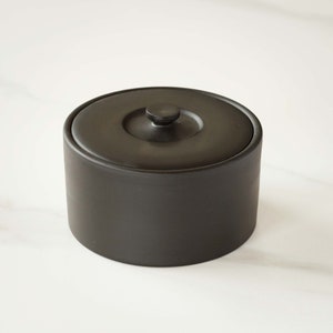 May include: A black ceramic ice bucket with a lid and a small knob on top.