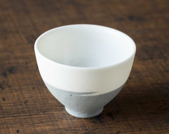 May include: A white ceramic bowl with a gray rim. The bowl is sitting on a wooden surface.