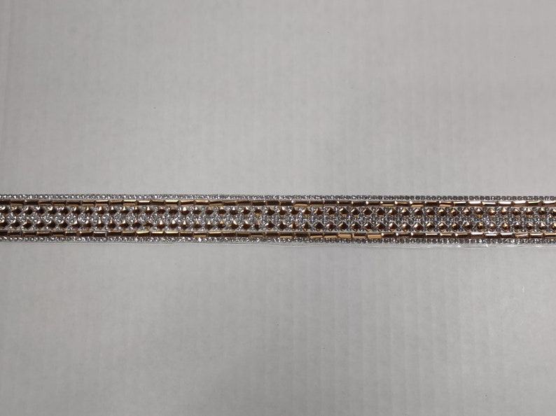 May include: A gold and silver trim with a repeating pattern of small, clear rhinestones.