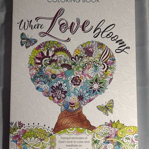 May include: A coloring book cover with a heart-shaped tree with flowers and butterflies. The title of the book is "Where Love Blooms". The text below the image says "Tranquil reminders of God's love to color and meditate on."