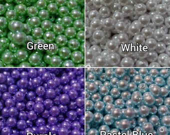 May include: Assortment of pearl beads in four colors: green, white, purple, and pastel blue. The beads are all the same size and shape, and they are arranged in a grid pattern.