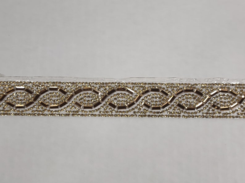 May include: Gold and clear beaded trim with a wavy pattern.