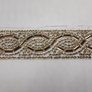 May include: Gold and clear rhinestone trim with a repeating pattern of small round rhinestones and larger rectangular rhinestones.