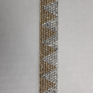 May include: A silver and gold trim with a repeating pattern of small round rhinestones.