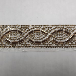 May include: A gold and clear rhinestone trim with a repeating pattern of small and large rhinestones.