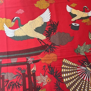 Op de afbeelding: Rode stof met een Japans geïnspireerd ontwerp met kranen, wolken, vissen, een torii-poort en waaiers. De stof is perfect voor knutselprojecten zoals draagtassen, kussens en quilts.