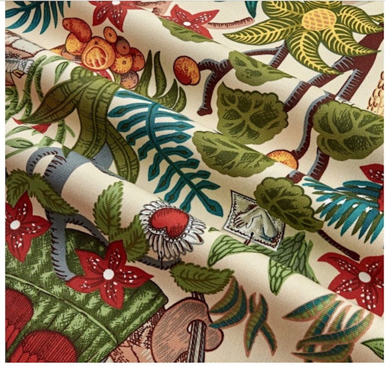May include: A beige fabric with a colorful tropical print. The print features green leaves, red flowers, and yellow fruit. The fabric has a textured surface.