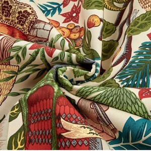 May include: A beige fabric with a colorful, intricate pattern. The pattern features a variety of motifs, including birds, flowers, and geometric shapes. The fabric is soft and has a slightly textured surface.