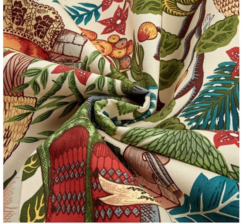 May include: A beige fabric with a colorful, intricate pattern. The pattern features a variety of motifs, including birds, flowers, and geometric shapes. The fabric is soft and has a slightly textured surface.