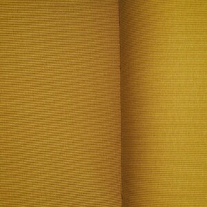 May include: Close-up of two pieces of fabric, both a deep mustard yellow. The fabric on the left has a subtle ribbed texture, while the fabric on the right has a smooth, slightly shiny surface.