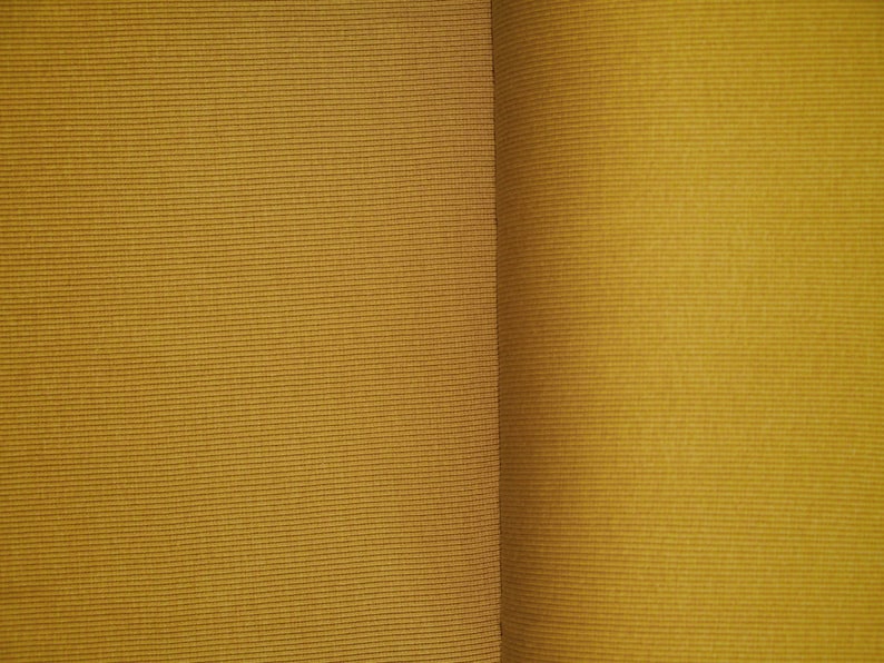 May include: Close-up of two pieces of fabric, both a deep mustard yellow. The fabric on the left has a subtle ribbed texture, while the fabric on the right has a smooth, slightly shiny surface.