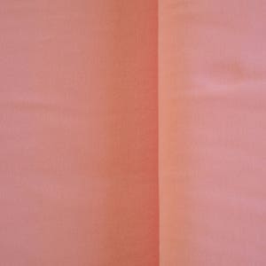 May include: A close-up of a smooth, peach-colored fabric surface. The fabric is divided into two sections by a vertical seam.