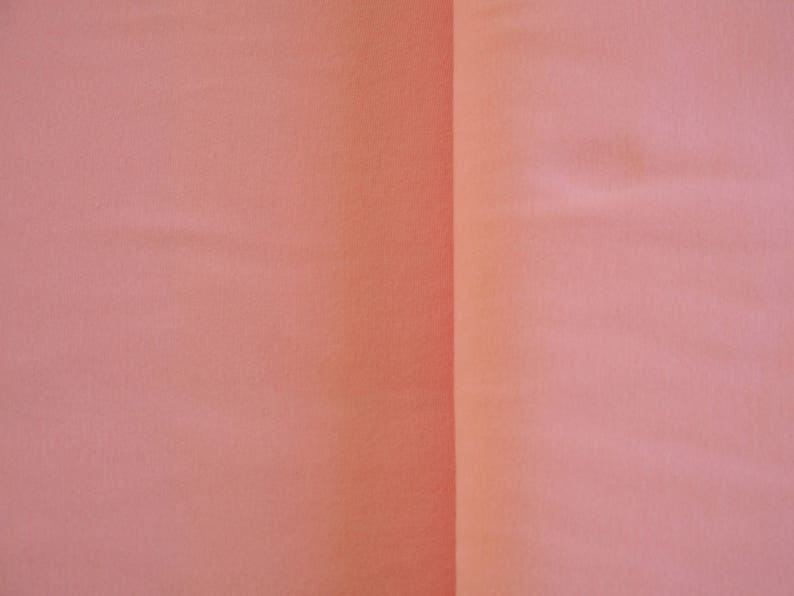 May include: A close-up of a smooth, peach-colored fabric surface. The fabric is divided into two sections by a vertical seam.