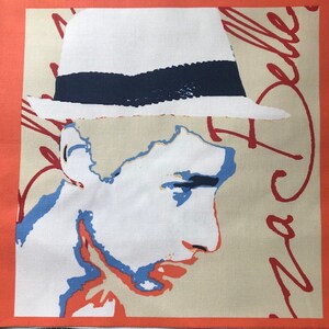 May include: A white hat with a blue band, a red signature, and a colorful portrait of a person with a white background.