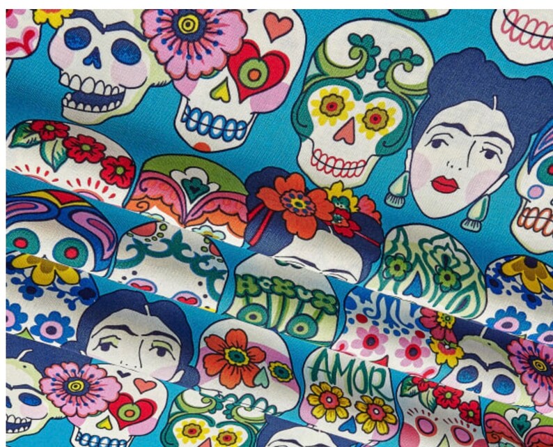 May include: A blue fabric with a repeating pattern of colorful sugar skulls and floral designs. The skulls have black eyes and are decorated with flowers and hearts. The fabric also features images of women with flowers in their hair.