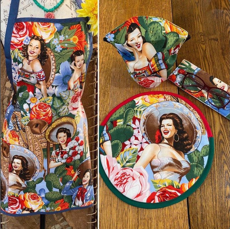 May include: A colorful apron with a floral pattern and images of women. The apron has a blue background with red, yellow, and green flowers. The women are wearing various outfits and have different hairstyles. The apron is perfect for adding a touch of vintage style to any kitchen.