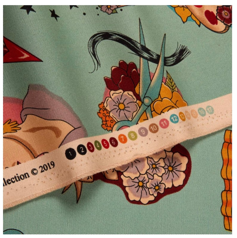 May include: Close-up of a fabric with a light blue background and a repeating pattern of floral and barber-themed illustrations. The design includes scissors, flowers, and a woman's face. A white fabric strip with color swatches and the text "collection &copy; 2019" is across the image.